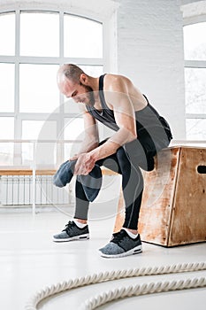 Perspiring fit sportsman resting after hard cross workout in light hall