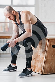 Perspiring fit sportsman resting after hard crossfit workout in light hall