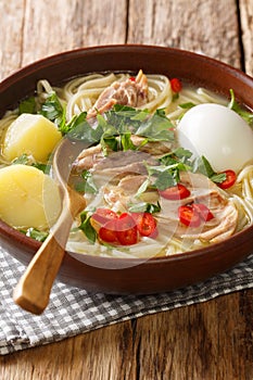 Peruvian caldo de gallina chicken noodle soup close-up in a plate. vertical