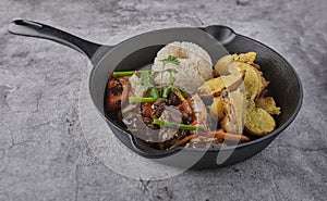 Peruvian d food - Lomo saltado - beef tenderloin with purple onion, yellow pepper, tomatoes served in a black pan with