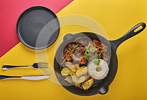 Peruvian d food - Lomo saltado - beef tenderloin with purple onion, yellow pepper, tomatoes served in a black pan with