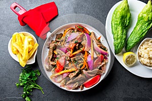 Peruvian dish Lomo saltado - beef tenderloin with purple onion, yellow chili, tomatoes in pan. Tot view