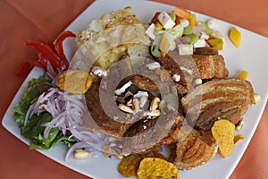 Peruvian food, Chicharron (fried pork) with potatoes, onion garnish, canchita. photo