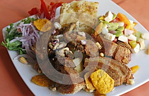 Peruvian food, Chicharron (fried pork) with potatoes, onion garnish, canchita.