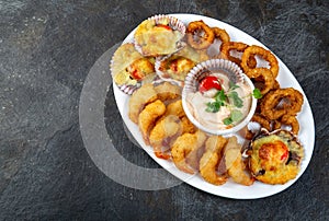 PERUVIAN FOOD. Piqueo caliente. Hot seafood platter fried shrimps, squid rings and baked scallops with sauce