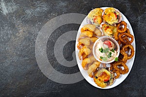 PERUVIAN FOOD. Piqueo caliente. Hot seafood platter fried shrimps, squid rings and baked scallops with sauce