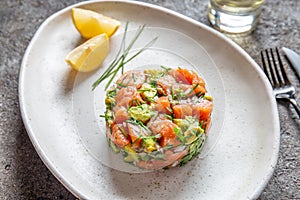 PERUVIAN FOOD. Salmon ceviche with avocado, spring onion and lemon on white plate served with white wine photo