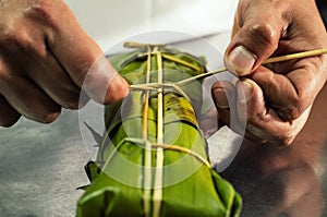 Peruvian hands tying a traditional tamale with banana leaves. photo