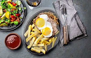 Peruvian Latin American food. Lomo a lo pobre. Beef whit fried potatoes french fry and eggs. served with salad. Top view photo