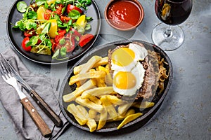 Peruvian Latin American food. Lomo a lo pobre. Beef whit fried potatoes french fry and eggs. served with salad. Top view photo