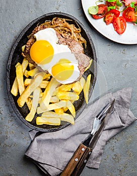 Peruvian Latin American food. Lomo a lo pobre. Beef whit fried potatoes french fry and eggs. served with salad. Top view photo