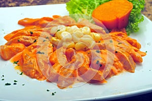 Peruvian recipe of fish tiradito with cooked corn, lots of yellow sauce