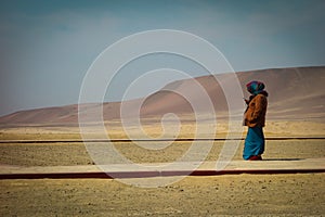 Peruánsky žena v tradičný oblečenie vzhľad na mobil stojace na hornatý oblasť 