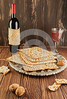 Pesach celebration concept - Jewish holiday Pesach. Matzah on traditional Seder plate with bottle of red wine, glass of