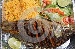 Pescado Frito, a Mexican dish with fried tilapia, yellow rice and salad