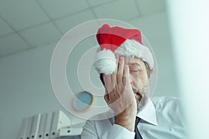 Pessimistic businessman with Santa Claus hat suffering from Christmas holiday season depression