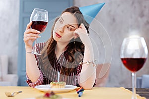 Pessimistic dark-haired woman looking at glass of wine