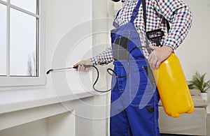 Pest control exterminator spraying poisonous chemicals over windows inside the house