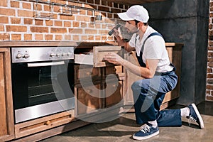 pest control worker examining cabinet in kitchen
