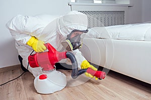 Pest control worker lying on floor and spraying pesticides in bedroom