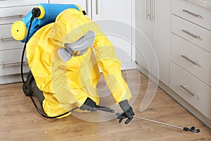 Pest control worker in protective suit spraying pesticide