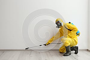 Pest control worker in protective suit spraying pesticide. Space for text