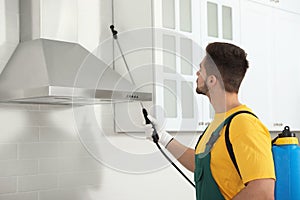 Pest control worker spraying insecticide on furniture