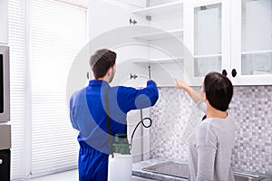 Pest Control Worker Spraying Insecticide On Shelf