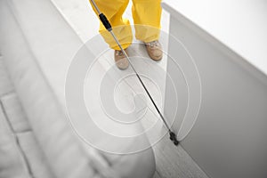 Pest control worker spraying pesticide around furniture, above view