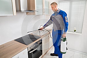 Pest Control Worker Spraying Pesticide On Induction Hob