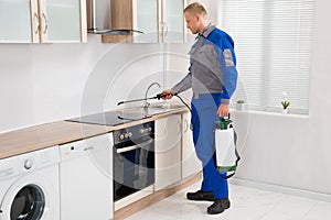Pest Control Worker Spraying Pesticide On Induction Hob photo