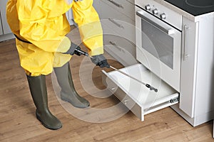 Pest control worker spraying pesticide in kitchen, closeup