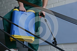 Pest control worker spraying pesticide on stairs, closeup