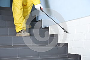 Pest control worker spraying pesticide on stairs indoors, closeup