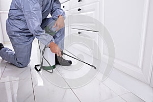 Pest Control Worker Spraying Pesticide On White Cabinet