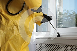 Pest control worker spraying pesticide on window sill, closeup