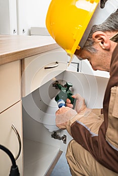 Pest control worker spraying pesticides inside cabinet