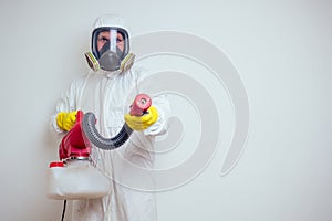 Pest control worker spraying pesticides with sprayer in apartment copy spase white walls background