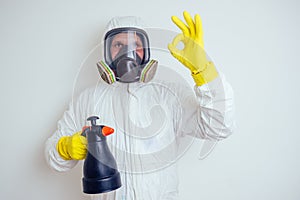 Pest control worker spraying pesticides with sprayer in apartment copy spase white walls background photo