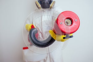 Pest control worker spraying pesticides with sprayer in apartment copy spase white walls background photo