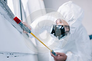 pest control worker spraying pesticides under windowsill