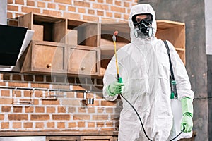 pest control worker in uniform standing with sprayer