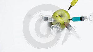 Pesticides, nitrates, gmo and other chemicals are injected into green apple with syringes. Top view.