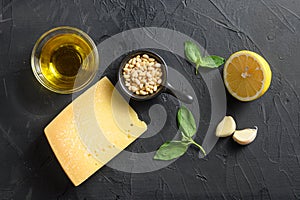 Pesto alla Genovese , Basil Sauce ingredients over black stone background Parmesan cheese, basil leaves, pine nuts, olive oil,