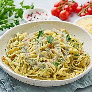 Pesto pasta, bavette with walnuts, parsley, garlic, nuts, olive oil. Side view, close-up, blue background.