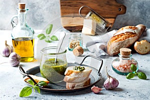 Pesto sauce in glass jar with ingredients.. Basil, olive oil, parmesan, garlic, pine nuts.