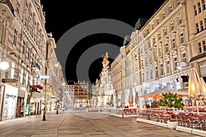 Pestsaule between illuminated buildings during night at Graben street in Vienna, Austria