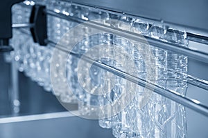 The PET bottles hanging on  the rail on the conveyor belt for filling process in the drinking water factory.