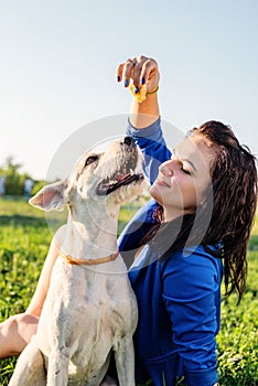 Young attractive woman feeding her dog in the park in summer day