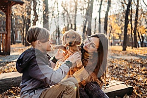 Pet care advice for autumn. Happy family mother and teen boy son walking and having fun with cocker spaniel puppy